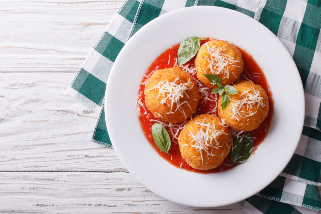 fried arancini rice balls with tomato sauce on the table.