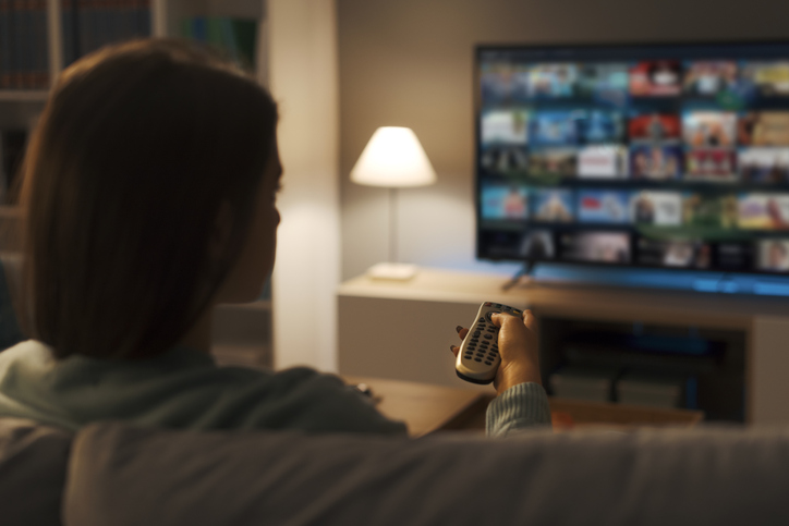 Young woman watching video on demand on her TV