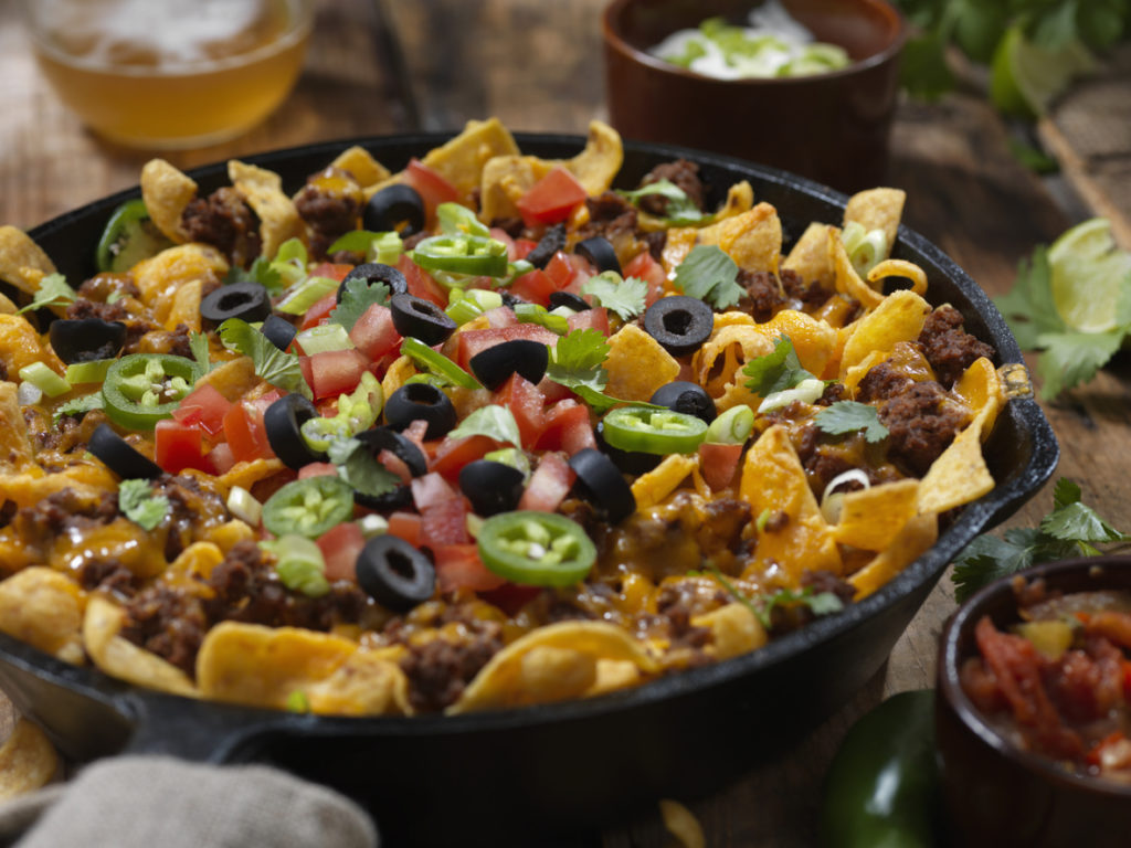 Baked Frito Pie with Black Olives, Tomatoes, Green Onions, Jalapenos, Salsa, Guacamole, and Sour Cream